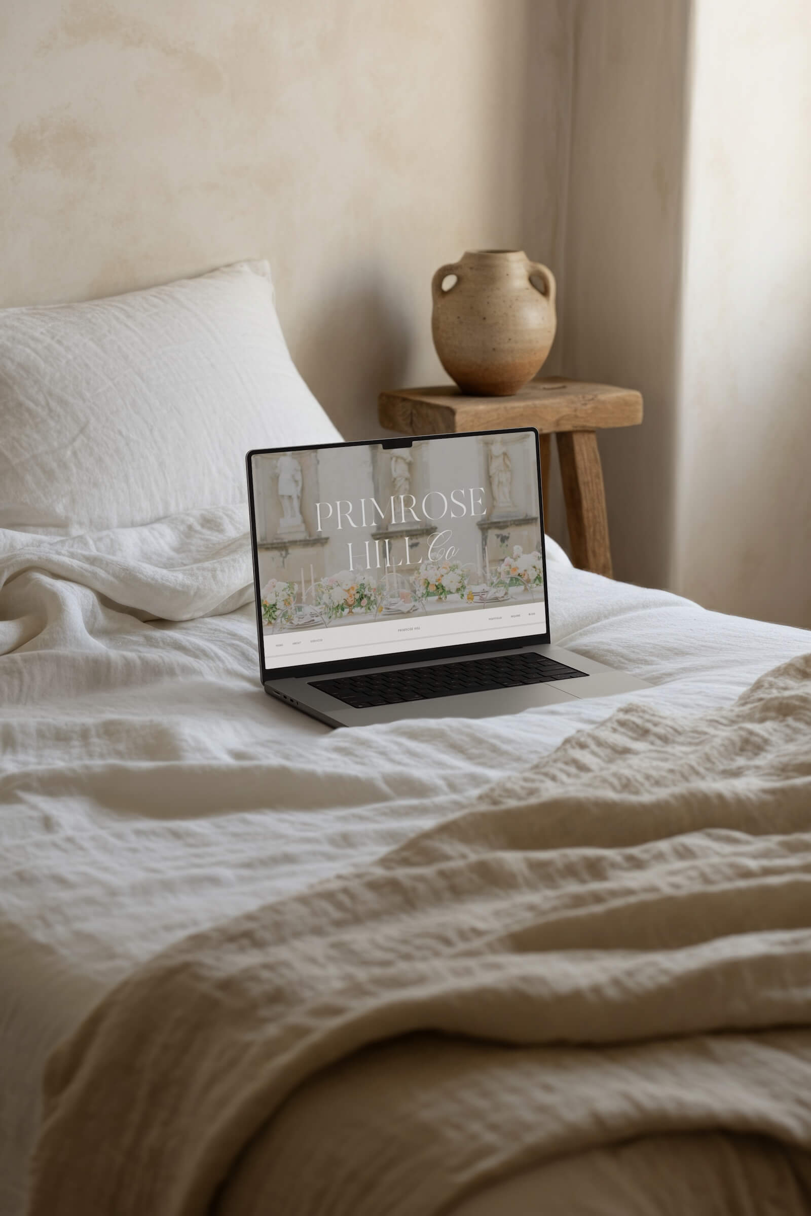 fine art wedding photography website template displayed on laptop in a beige interior setting on a bed